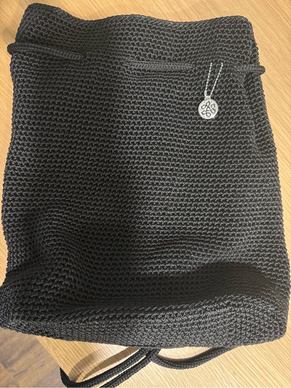 The Sak Black Knit Drawstring Backpack with Silver Logo Charm